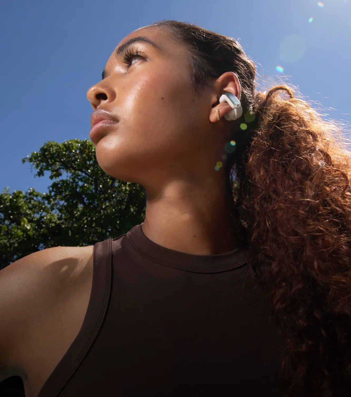A woman wearing Bose Ultra Open Earbuds outdoors.