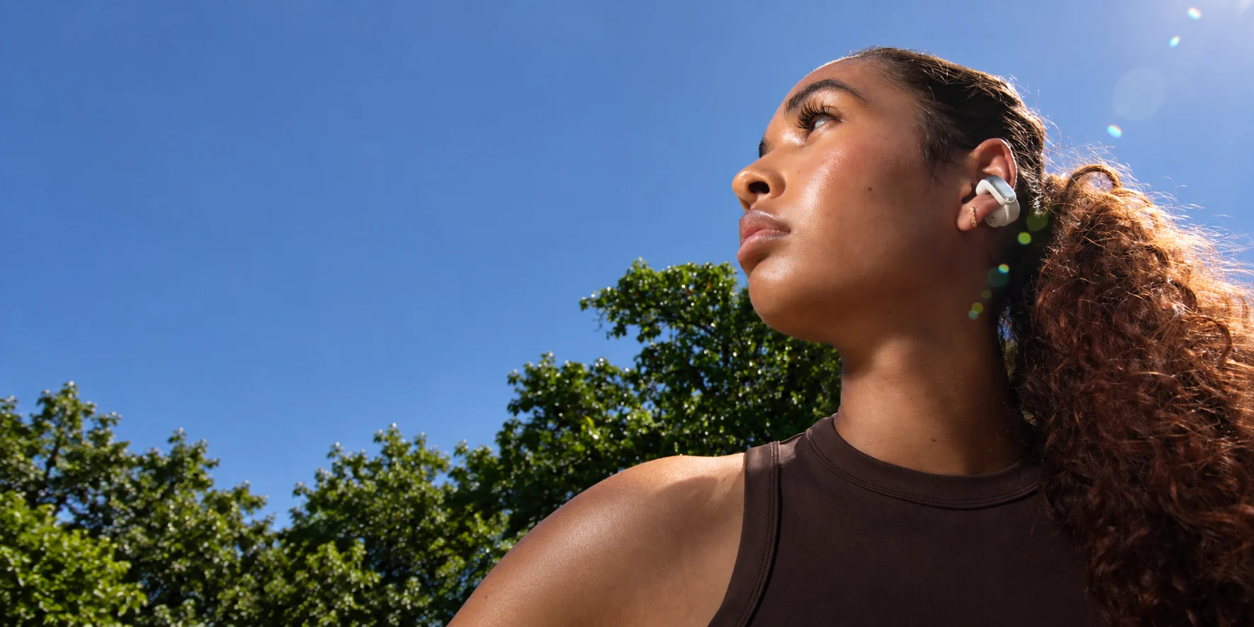 A woman wearing Bose Ultra Open Earbuds outdoors.